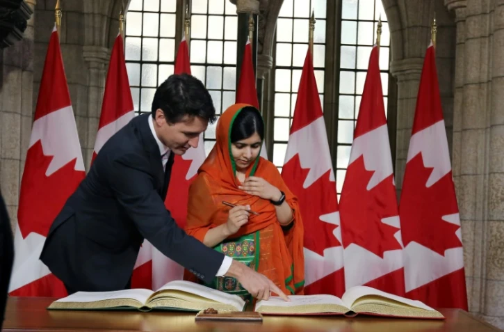 Malala Yousafzai signe un livre d'or avec Justin Trudeau, au Parlement Ă Ottawa le 12 avril 2017