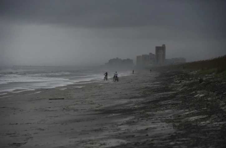 Des cyclistes sur une plage d'Atlantic Beach balayée par des vents violents, le 5 octobre 2016 en Floride à l'approche de l'ouragan Matthew  