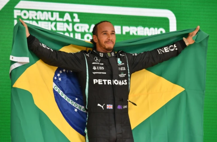 Le pilote britannique Lewis Hamilton (Mercedes) célèbre sur le podium, avec le drapeau brésilien, sa victoire dans le Grand Prix du Brésil de Formule 1, le 14 novembre sur le circuit d'Interlagos à Sao Paulo