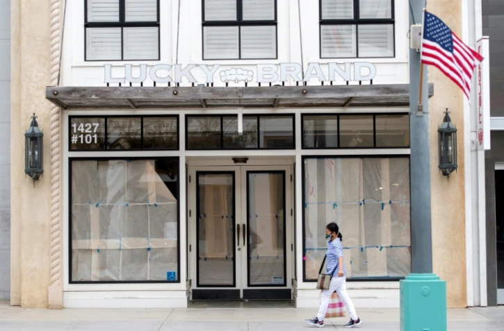 Une passante portant un masque marche devant un magasin fermé à Santa Monica en Californie, en pleine épidémie de coronavirus, le 28 juillet 2020