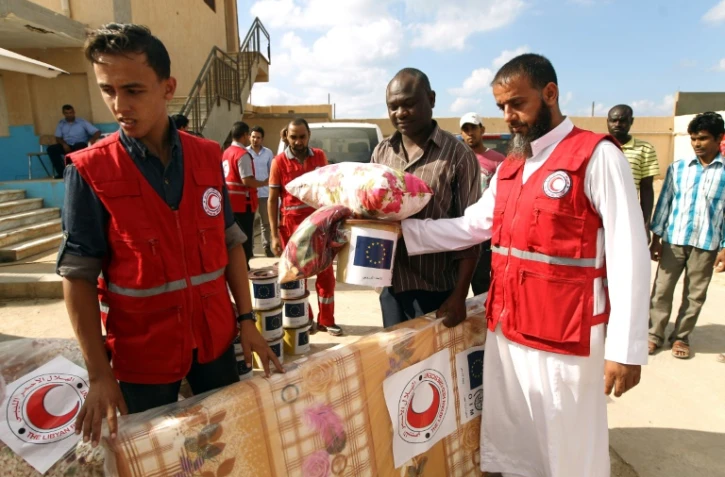 Des membres du Croissant Rouge lybien distribuent de l'aide aux migrants détenus à Tulmitha, à 100 km à l'est de Benghazi, le 16 août 2016