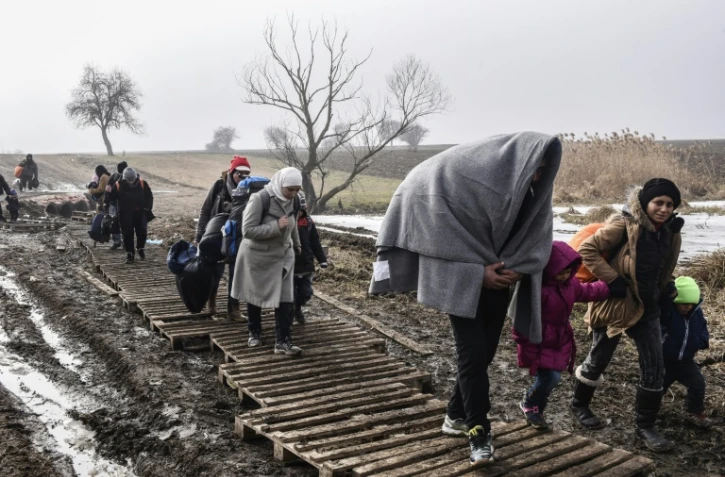 Des migrants traversent un champ boueux après avoir passé la frontière serbo-macédonienne près du village serbe de Miratovac, le 27 janvier 2016