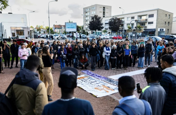 Des personnes autour d'une pancarte commémorant le nom des huit migrants décédés en tentant de traverser la Manche, à Calais, le 16 septembre 2024