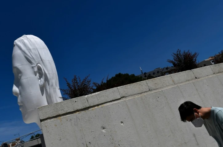 Devant la sculpture "Julia" de l'artiste espagnol Jaume Plensa sur la Plaza ColĂłn Ă Madrid le 21 mai 2020