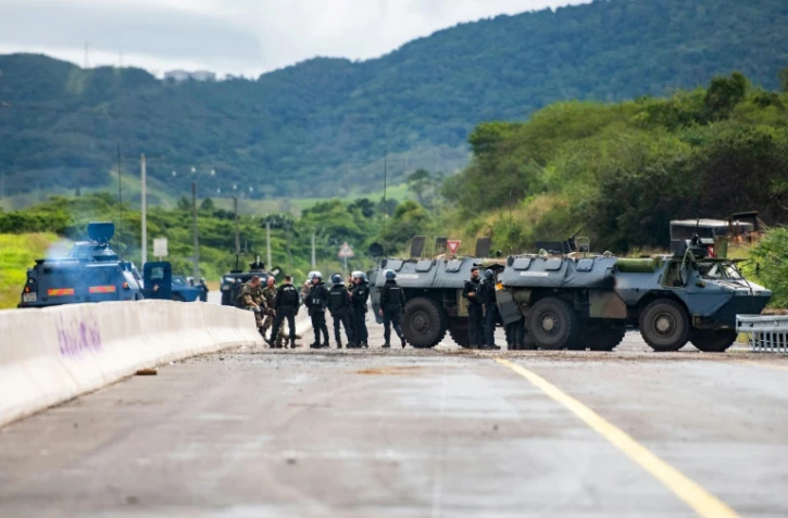 Des gendarmes mobiles sécurisent la zone pendant une opération de nettoyage de la route menant à l'aéroport de Nouméa dans le quartier de Païta, en Nouvelle-Calédonie, le 19 mai 2024