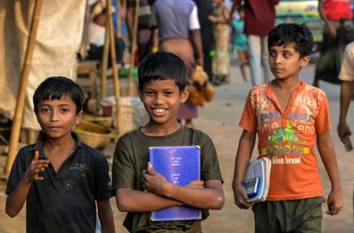 Des enfants réfugiés rohingyas portent leurs manuels scolaires au camp de réfugiés de Kutupalong, le 17 décembre 2025 à Ukhia, au Bangladesh