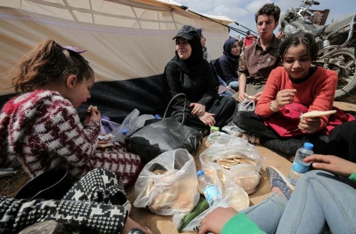 Des manifestants palestiniens mangent près d'une tente le 30 mars 2018 lors d'une manifestation près de la frontière avec Israël, dans le sud de la bande de Gaza