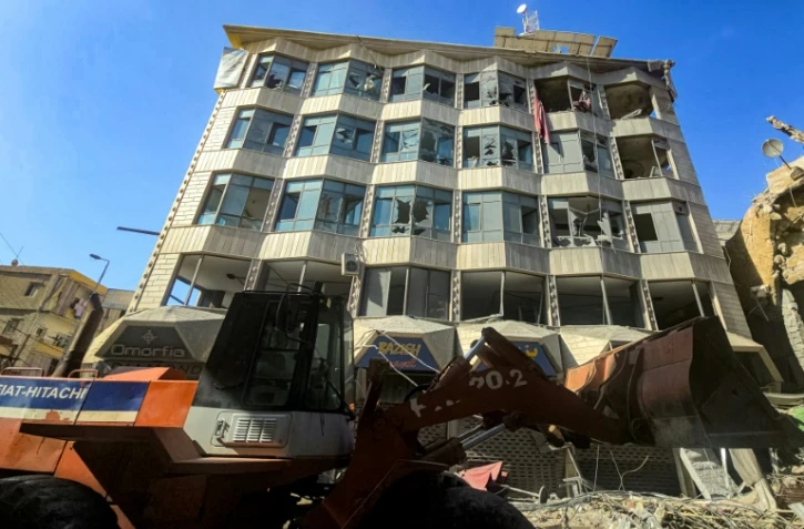 Un bulldozer déblaye des débris et gravats devant un bâtiment endommagé après des bombardements israéliens nocturnes sur la ville de Tyr, dans le sud du Liban, le 16 mai 2026