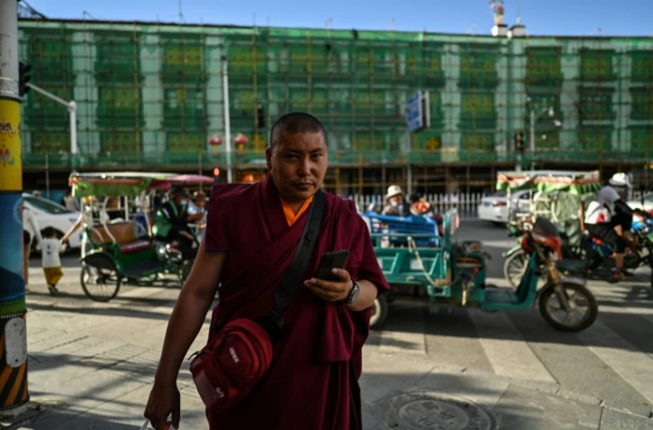 Un moine bouddhiste marche près d'un immeuble en reconstruction le 1er juin 2021 à Lhassa dans la région autonome du Tibet
