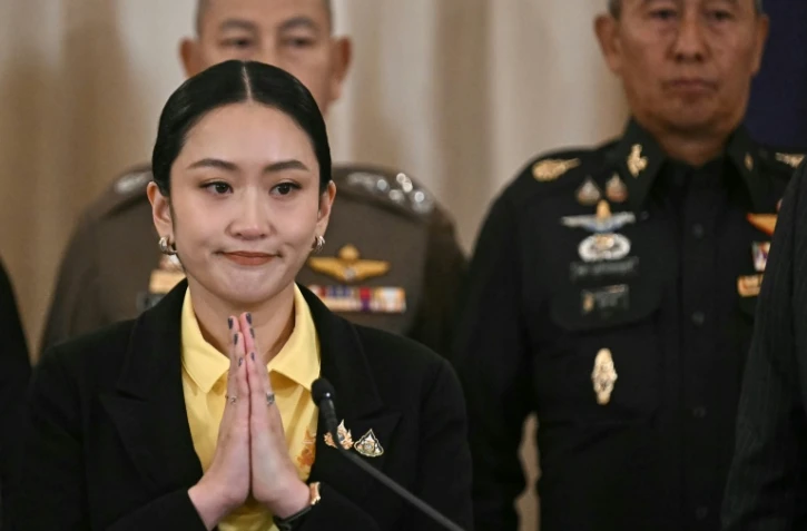 La Première ministre thaïlandaise Paetongtarn Shinawatra (g) joint ses mains lors d'une conférence de presse aux côtés du commandant des forces armées Pana Klaewplodthuk (d) au siège du gouvernement à Bangkok, le 19 juin 2025