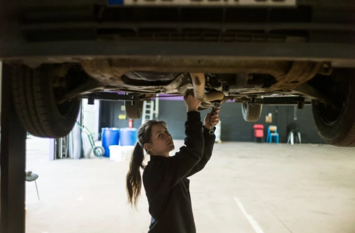 Une femme mécanicienne répare une voiture le 14 mai 2014 à Saint-Ouen-l'Aumone.