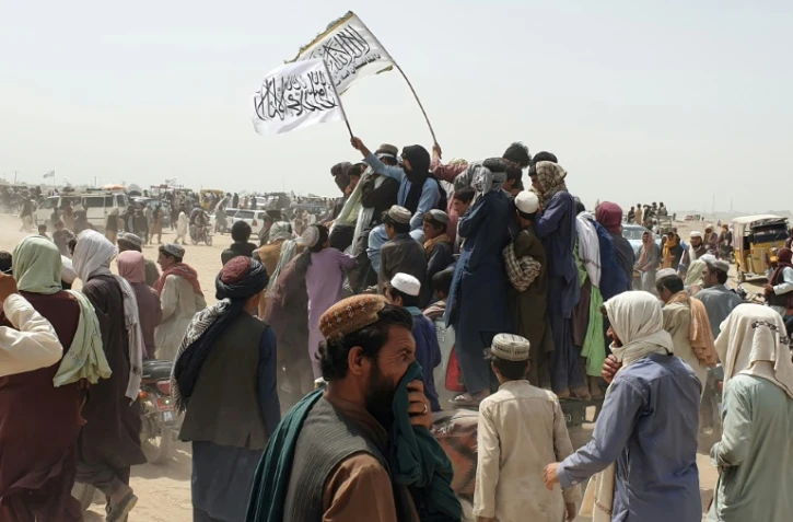 Des Afghans agitent des drapeaux talibans pour célébrer la prise de contrôle par les combattants islamistes d'un poste-frontière avec le Pakistan, à Spin Boldak, le 14 juillet 2021.