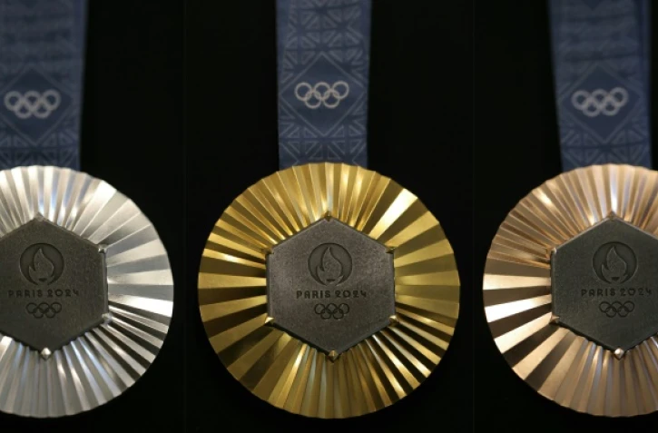 Combinaison de photos prises le 30 janvier 2024 à Paris montrant les médailles (argent, or et bronze, de gauche à droite) des prochains Jeux olympiques de Paris 2024 conçues par la maison française de joaillerie de luxe Chaumet et révélées au public le 8 février 2024.