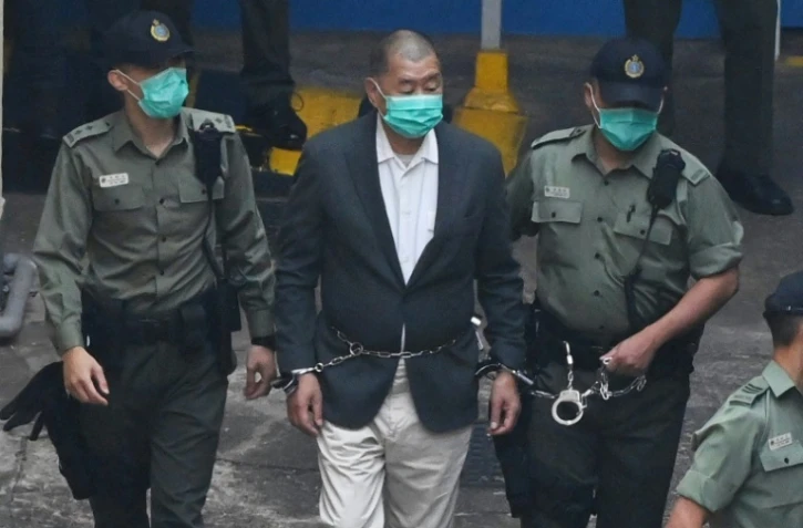 Jimmy Lai (c) est escorté par des policiers dans un véhicule de police pour se rendre au tribunal, à Hong Kong, le 12 décembre 2020