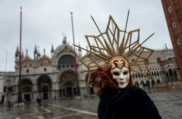 Un artisan vénitien portant un masque et un costume de carnaval sur la place Saint-Marc à Venise (Italie), le 7 février 2021
