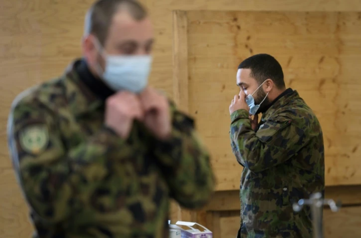 Deux militaires de l'armée suisse enfilent un masque de protection lors d'une formation à Bière (ouest) le 22 mars 2020