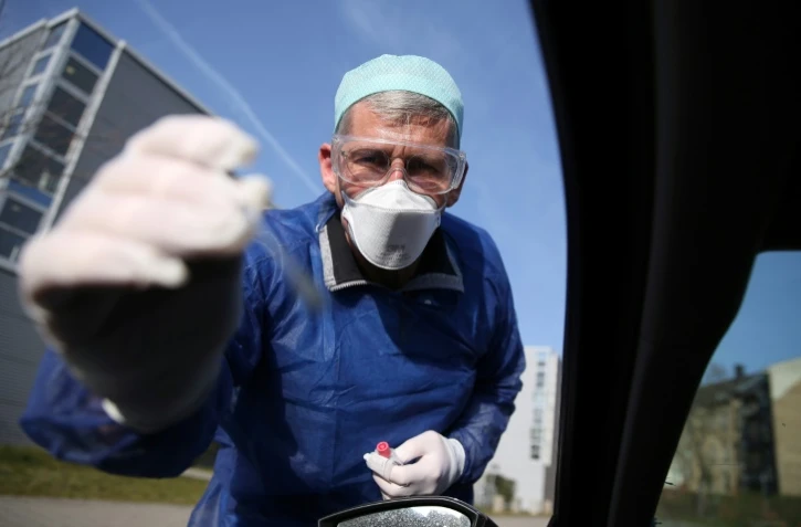 un médecin allemand teste un automobiliste pour vérifier s'il est positif ou non au coronavirus le 27 mars 2020 à Halle, dans l'est de l'Allemagne.
