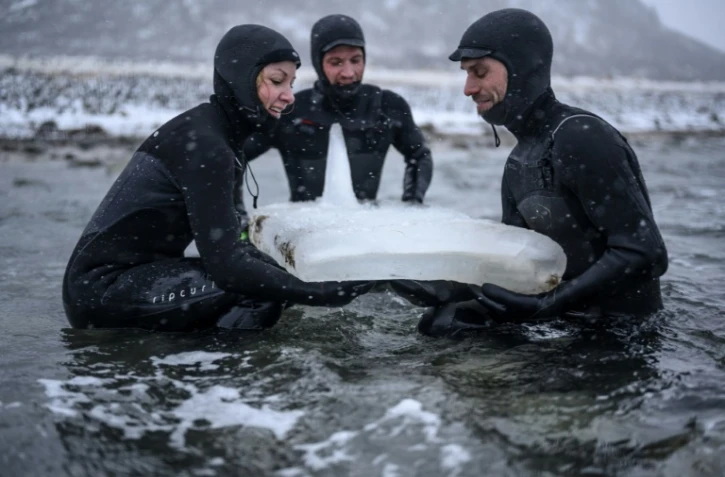 Des surfeurs suédois testent délicatement une planche en glace, près de Straumnes dans l'archipel des Lofoten, en Norvège, le 19 février 2019