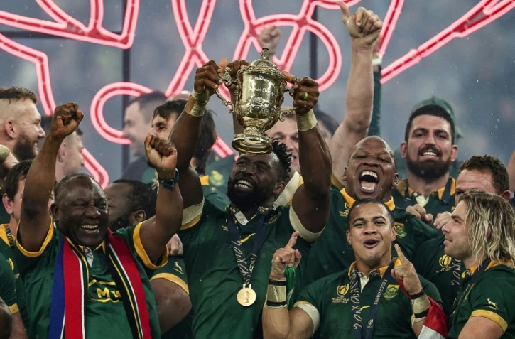 Le capitaine de l'Afrique du Sud Siya Kolisi (au centre) soulève le trophée Webb Ellis, aux côtés du Président de l'Afrique du Sud Cyril Ramaphosa (à gauche), l'ailier Cheslin Kolbe (deuxième à droite), et le demi de mêlée Faf de Klerk (à droite), après la victoire en finale du Mondial contre la Nouvelle-Zélande au Stade de France, près de Paris, le 28 octobre 2023