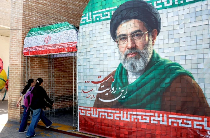 Des Iraniennes passent devant un portrait du nouveau guide suprême iranien, le 6 mai 2026 à Téhéran