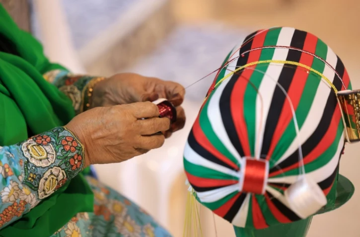 Une femme tresse des fils selon la méthode Al Talli, une technique de tissage locale traditionnelle, à Al-Ain, aux Emirats arabes unis, le 10 novembre 2023