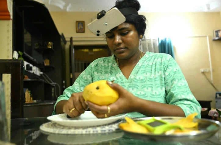 Nagireddy Sriramyachandra filme avec un téléphone ses gestes pendant qu'elle coupe une mangue pour entraîner un futur robot dopé à l'IA, le 15 mai 2026 à Madras, en Inde