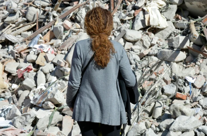 Une femme devant les décombres d'un immeuble détruit par le séisme à Amatrice, le 26 août 2016