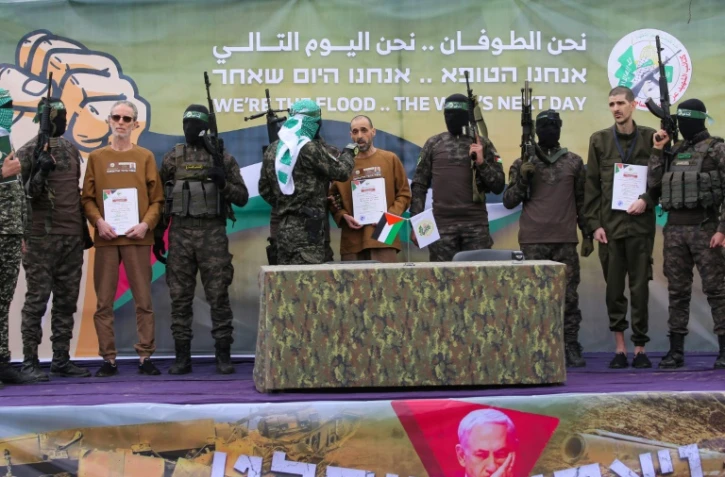 Des combattants palestiniens du Hamas encadrent trois otages israéliens sur un podium avant de les remettre à la Croix-Rouge à Deir el-Balah, dans le centre de Gaza, le 8 février 2025
