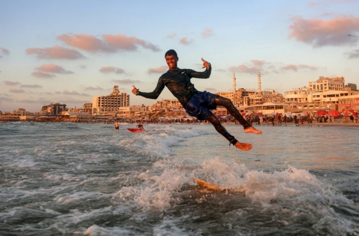 Un jeune Palestinien surfe au large d'une une plage de la ville de Gaza, le 21 juin 2026 