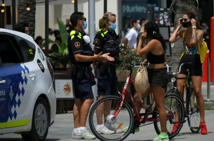 Des policiers municipaux demandent à des habitants de porter un masque de protection près d'une plage de Barcelone, le 9 juillet 2020