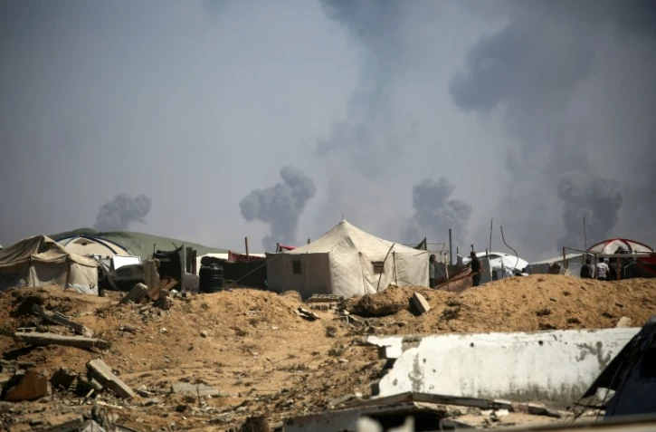 Des tentes de Palestiniens déplacés dans le camp de réfugiés de Nousseirat, dans le centre de la bande de Gaza, tandis que des panaches de fumée s'élèvent au-dessus de la ville de Gaza, bombardée par Israël, le 19 septembre 2025.