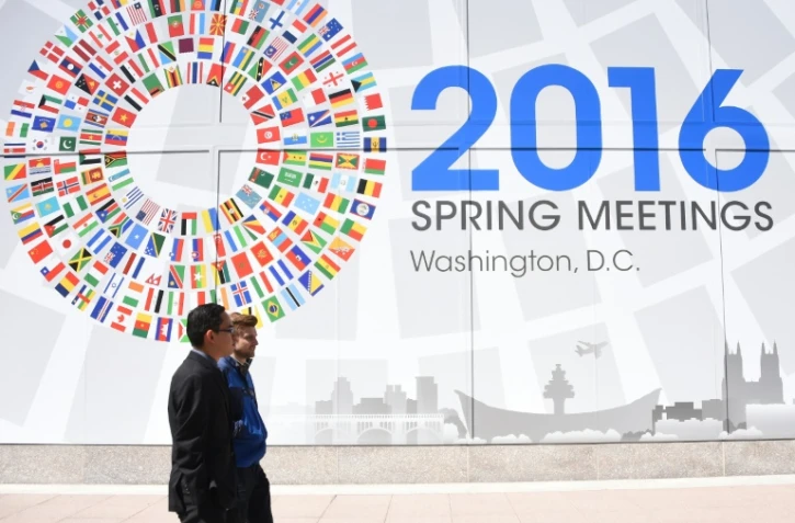 Deux hommes passent devant un panneau annonçant le meeting du monde de la finance à Washington, le 13 avril 2016