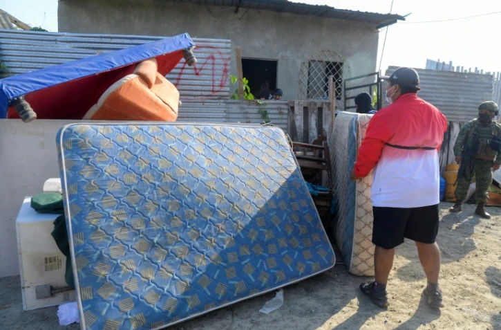 Un homme sort les meubles et les biens des personnes qui avaient extorqué et expulsé sa famille après avoir récupéré sa maison lors d'une opération de l'armée et de la police à Duran, le 23 juillet 2024 en Equateur