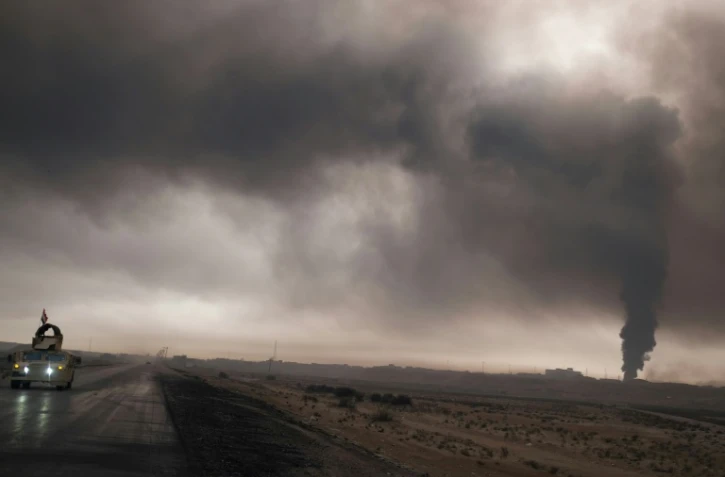 Un véhicule de l'armée irakienne emprunte une route près de Mossoul, sous la fumée d'un puits de pétrole enflammé par l'EI, le 4 novembre 2016.