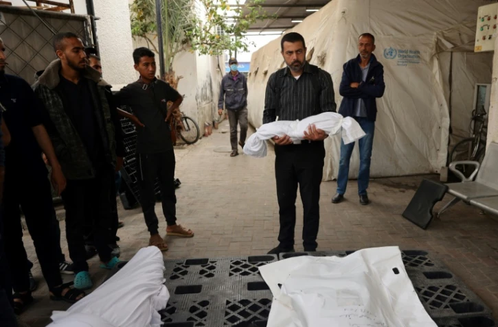 Un homme porte le corps d'un enfant tué lors d'un bombardement israélien, devant la morgue d'un hôpital de Rafah, dans le sud de la bande de Gaza, le 27 avril 2024