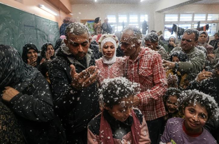 Afnan (centre), son père (à sa gauche) et son mari Mustafa (à droite) sont couverts de mousse lors de leur mariage dans le sud de la bande de Gaza, le 12 janvier 2024