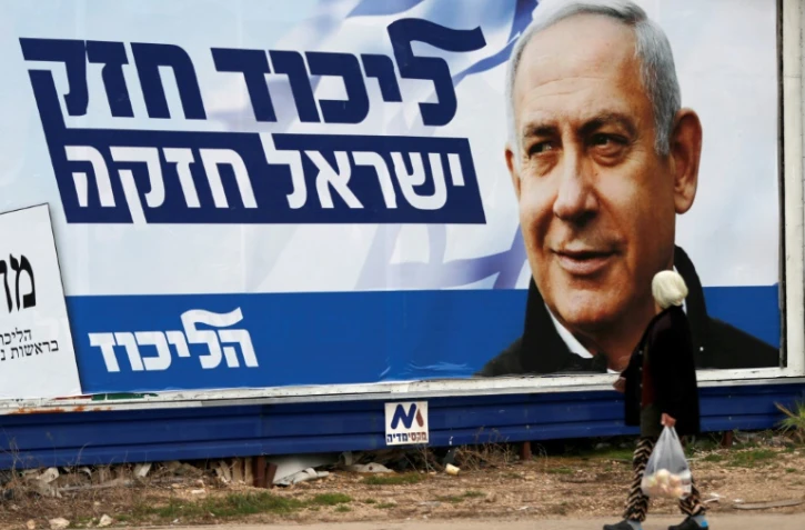 Une arabe israélienne marche devant une affiche électorale montrant le Premier ministre israélien Benjamin Netanyahu, à Haïfa (nord), le 4 avril 2019