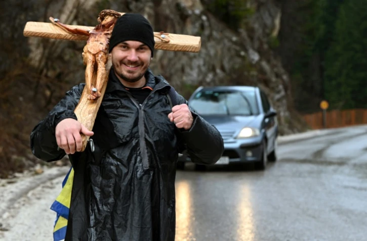 Josip Jelinic, une croix de 8 kilos sur l'épaule, marche le long d'une route pendant son pèlerinage de 1000 km demandant le pardon et la réconciliation de tous les peuples en Bosnie-Herzégovine, près de la ville de Vares, le 25 mars 2025