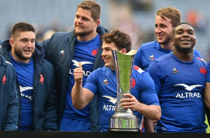 Antoine Dupont, capitaine et demi de mêlée du XV de France, tient en main le trophée de l'Auld Alliance au milieu de partenaires après la victoire 36-17 face à l'Ecosse le samedi 26 février 2022 à Edimbourg.