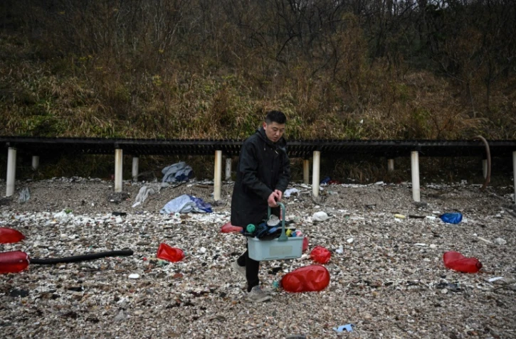 L'artiste chinois Fu Junsheng chemine sur le rivage des îles de l'archipel Miaodao à la recherche d'objets en plastique échoués, le 25 novembre 2024