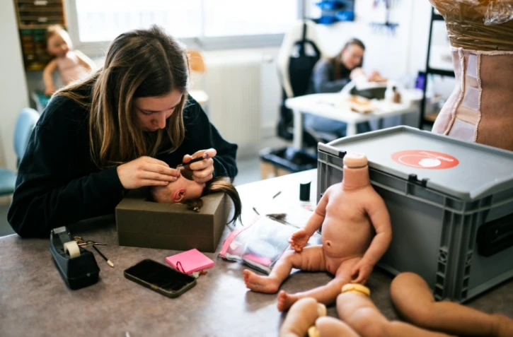Une technicienne d'atelier implante de la laine pour simuler une chevelure sur de faux bébés en silicone dans les locaux de l'entreprise Cinébébé, le 27 janvier 2025 à Saint-Denis, près de Paris