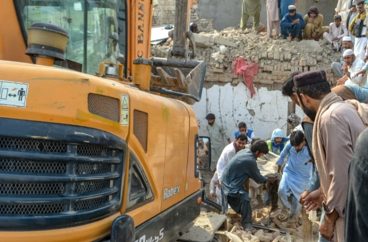 Des personnes transportent le corps d'une victime après un attentat contre un poste de contrôle de police à Bannu, dans le nord-ouest du Pakistan, le 10 mai 2026