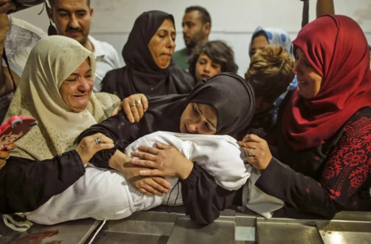 La mère de Leila al-Ghandour (C), un bébé palestinien de huit mois mort lundi après avoir inhalé des gaz lacrymogènes tirés par l'armée israélienne selon le ministère de la Santé à Gaza, tient le corps de son enfant à l'hôpital al-Shifa de Gaza, le 15 mai 2018