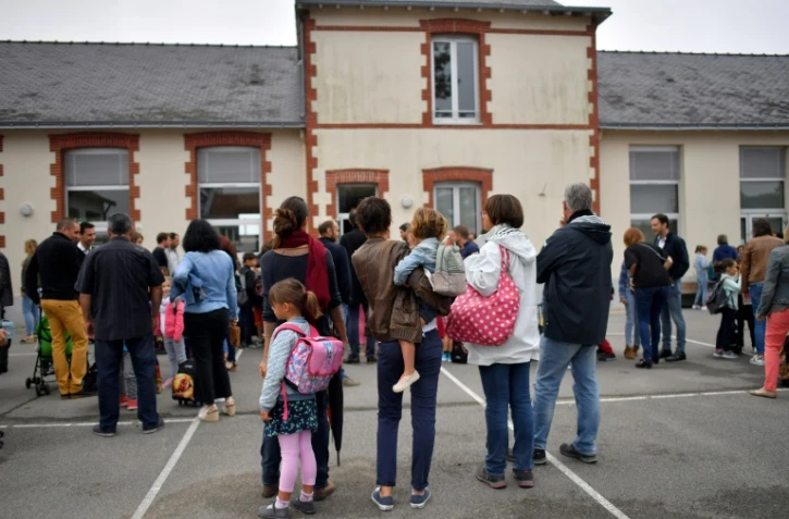 Des enfants et leurs parents devant une école primaire
