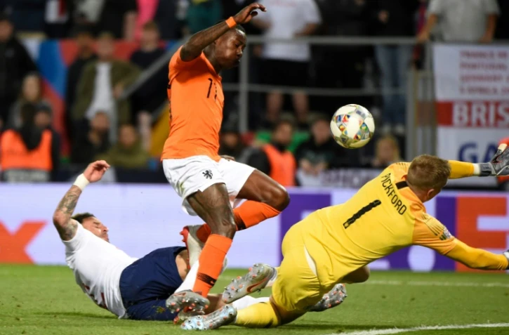 L'attaquant néerlandais Quincy Promes (c) entre le gardien de but anglais Jordan Pickford (d) et le défenseur Kyle Walker qui marque contre son camp en demi-finale de la Ligue des nations, le 6 juin 2019 à Guimaraes