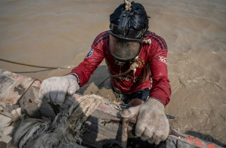 Un homme plonge dans les eaux boueuses du fleuve Yangon pour remonter des épaves, le 27 février 2024 à Rangoun, en Birmanie