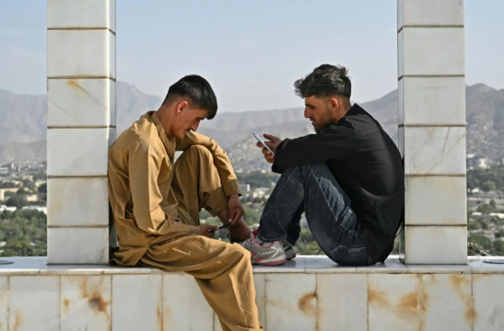 Des jeunes Afghans consultent leurs smartphones, sur la colline de Wazir Akbar Khan, à Kaboul, le 10 août 2026