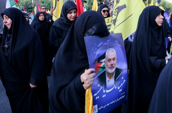 Une femme porte un portrait d'Ismaïl Haniyeh, lors d'une manifestation pour dénoncer sa mort, le 31 juillet 2024 sur la place de la Palestine à Téhéran