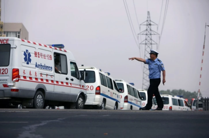 Un policier chinois indique le chemin à des ambulances à Dehui, le 3 juin 2013