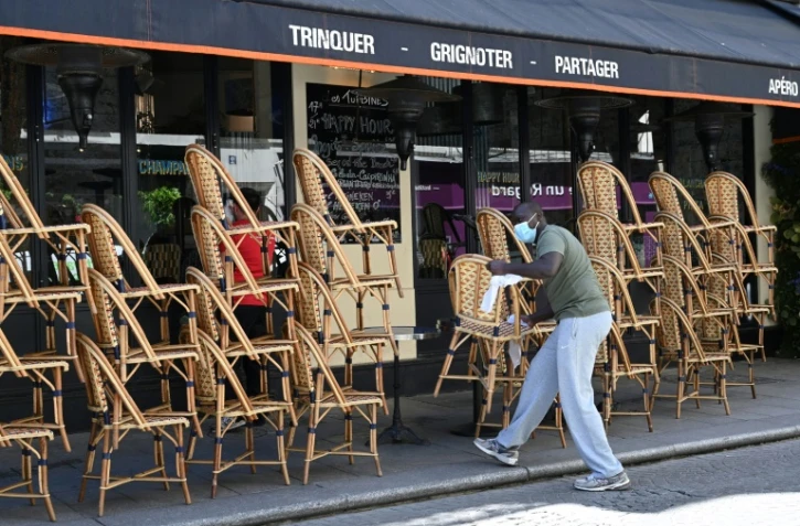 Un employé nettoie les chaises avant la réouverture des terrasses des cafés, bars et restaurants, le 30 mai 2020 à Paris